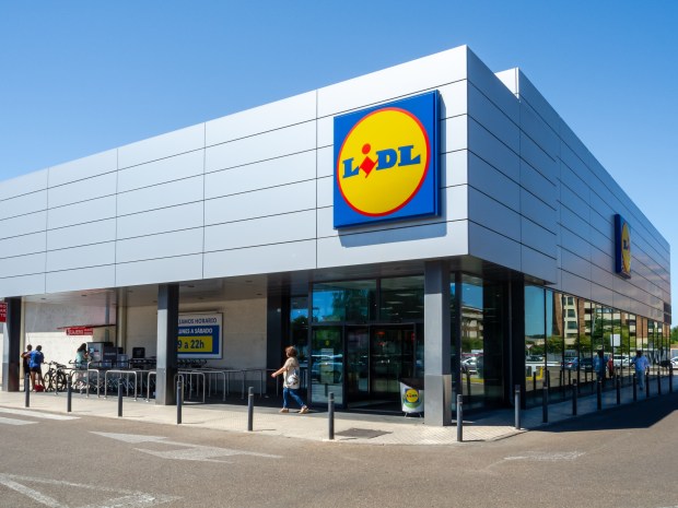 a woman walks into a lidl store on a sunny day