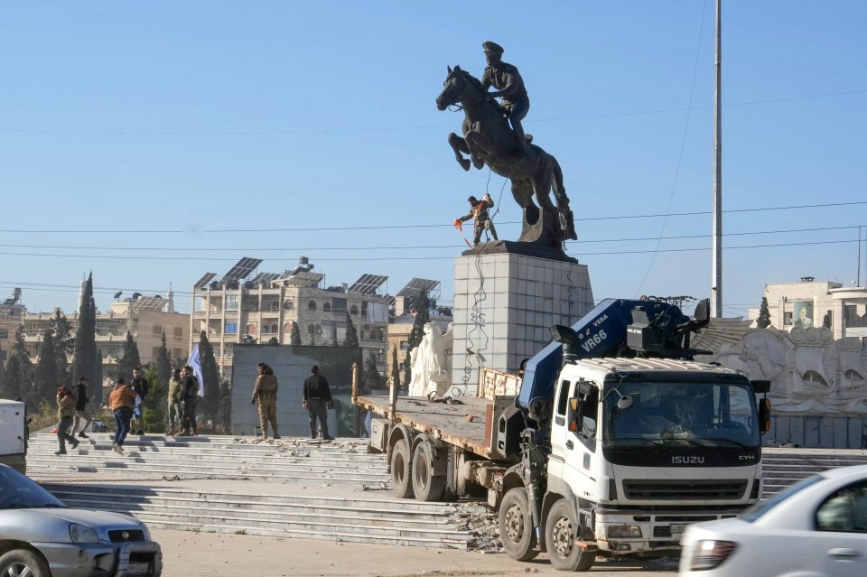 Anti-government fighters prepare to topple the equestrian statue of Bassel-al-Assad