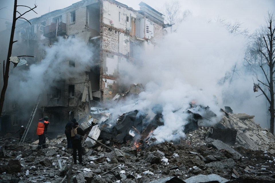 Rescuer and policemen stand amid rubble near collapsed wall of residential building after missile attack in Ukraine in January