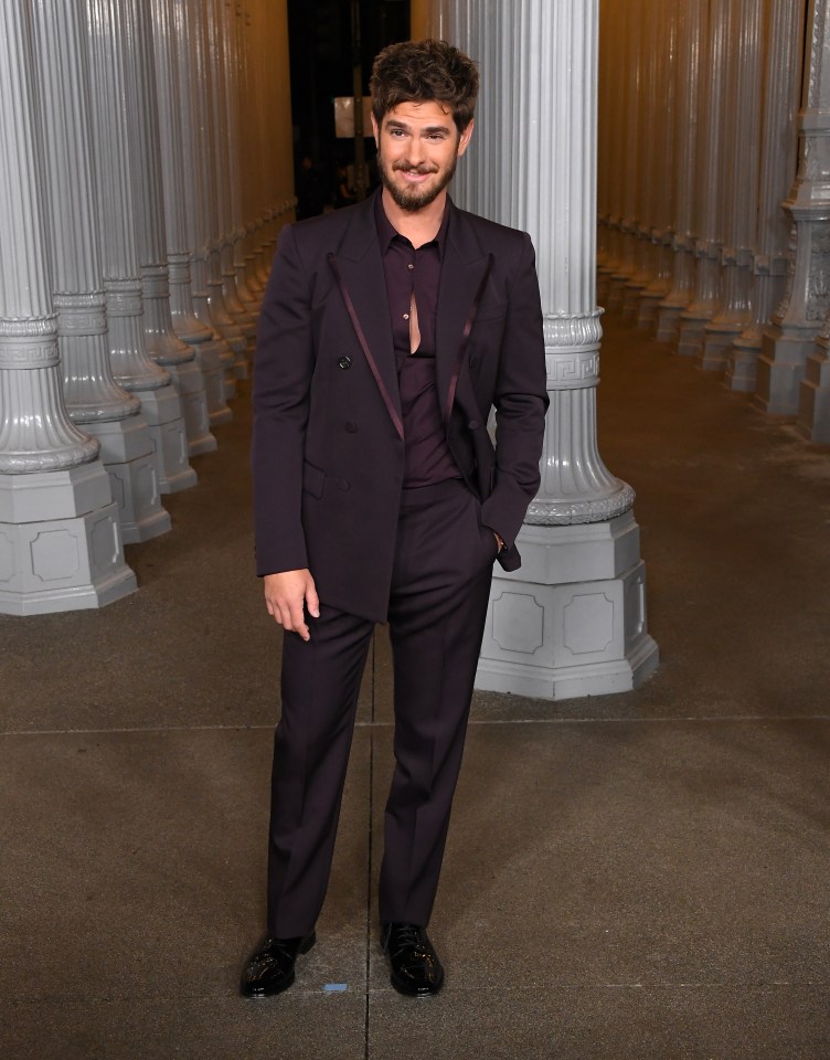 a man in a suit stands in front of columns