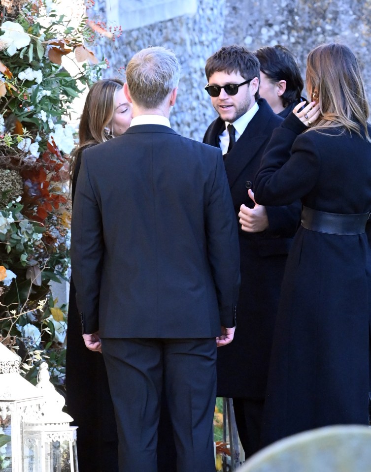 a man in sunglasses talks to a woman in a black coat