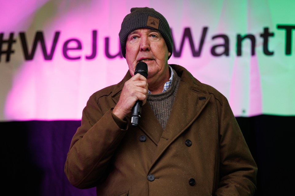 a man speaking into a microphone in front of a sign that says #weju want