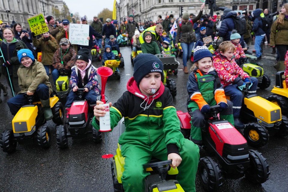 a boy wearing a john deere jacket rides a toy tractor