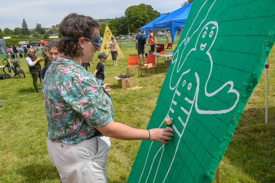 a woman wearing blindfolds draws on a green board