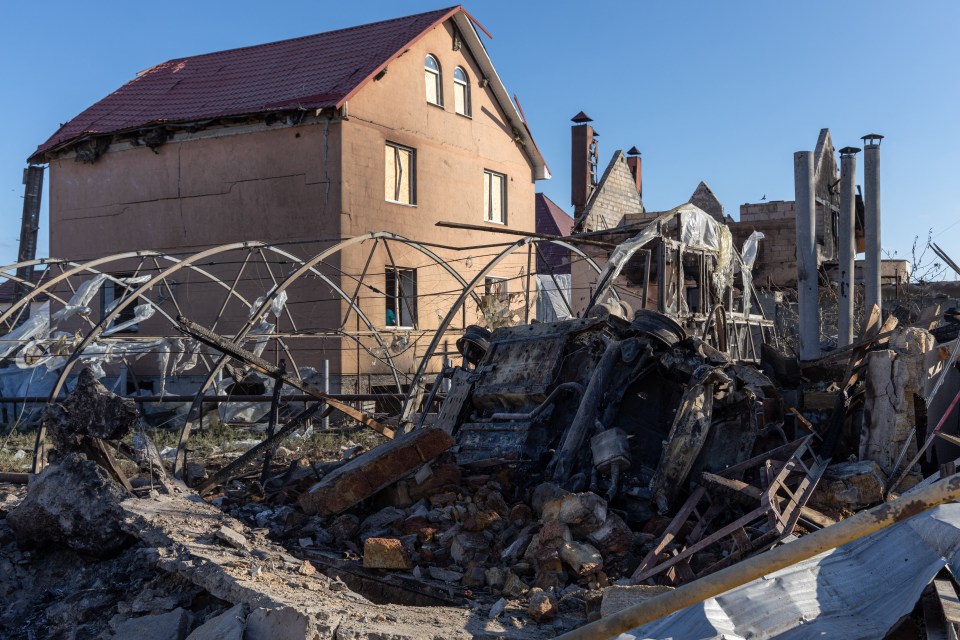 A destroyed car sits among debris from a damaged house following a missile attack