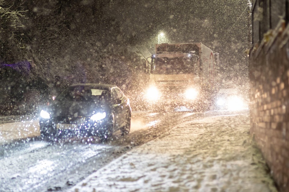 a car is driving down a snowy street at night