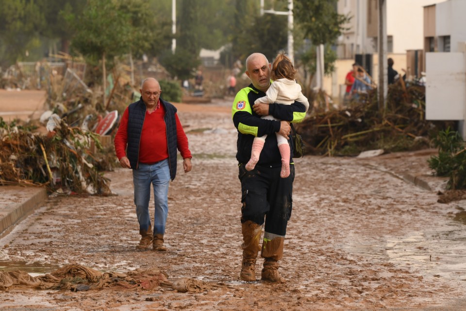 An emergency worker carries a child