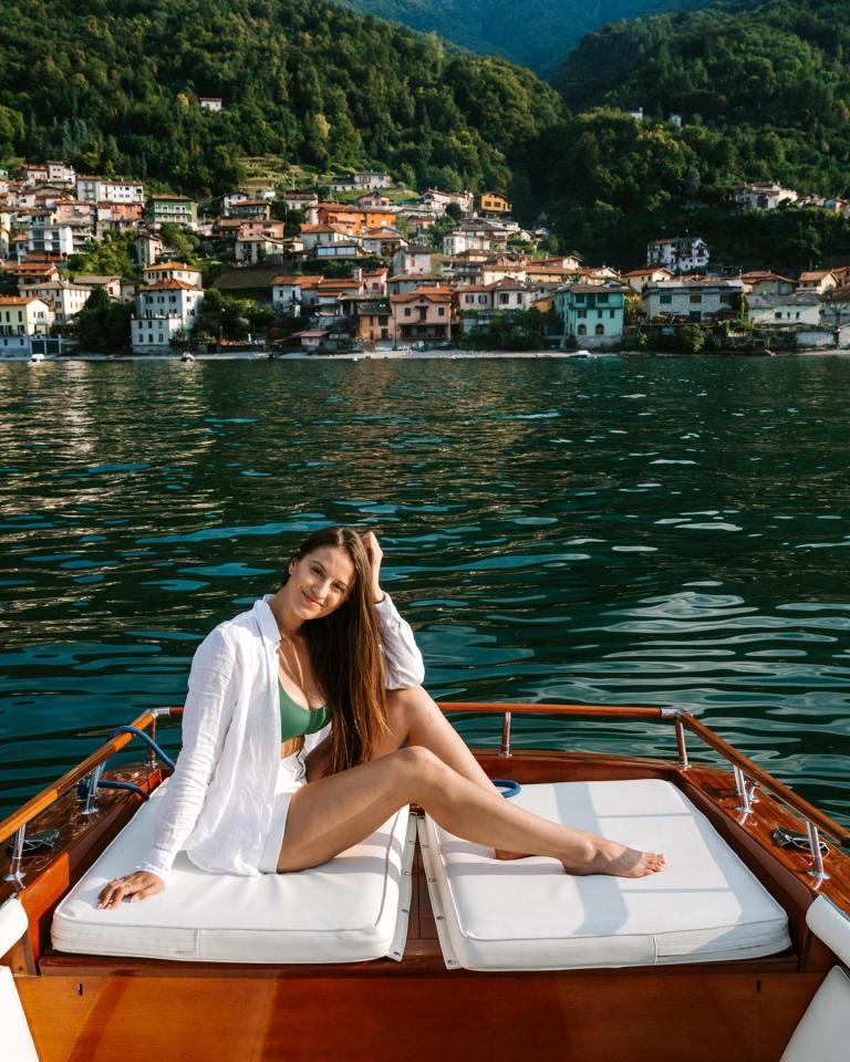 a woman sits on the back of a boat in the water