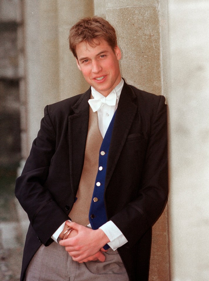 a young man in a suit and bow tie leans against a wall