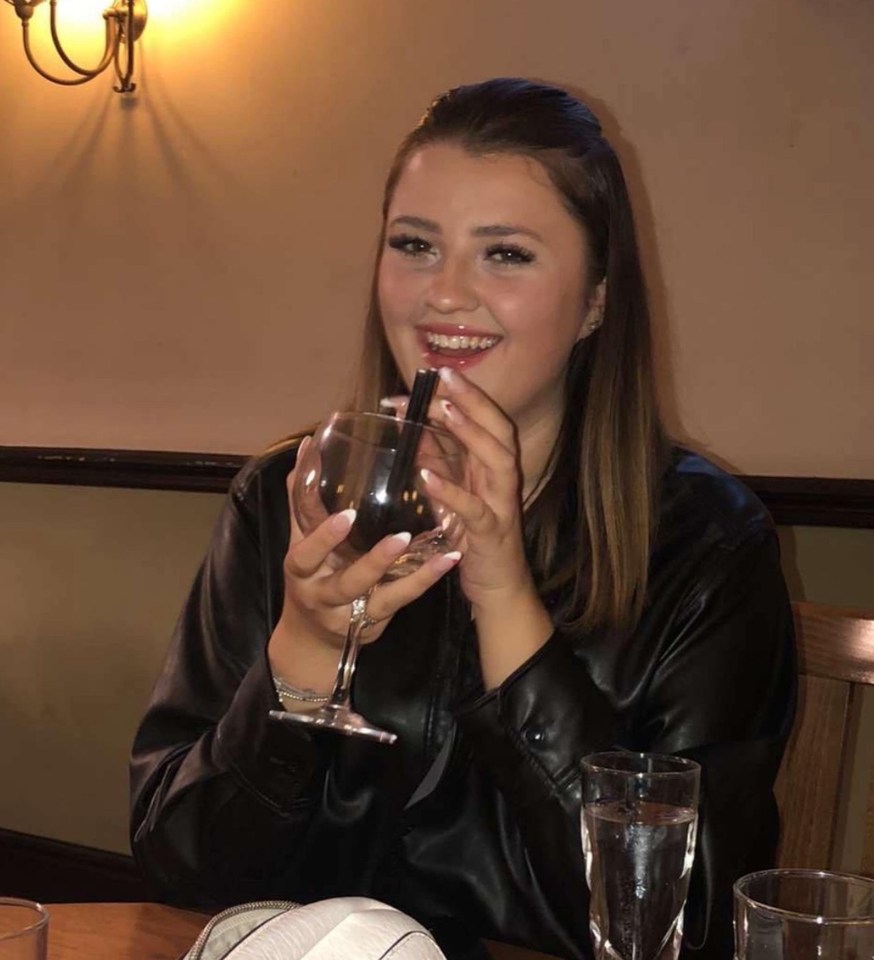 a woman drinking a glass of wine in front of a tv screen that says man protests