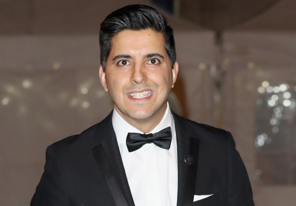 a man in a tuxedo stands on a red carpet