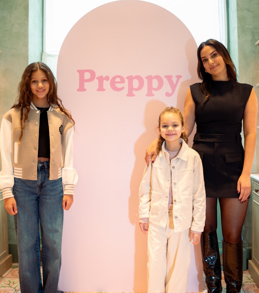 a woman and two girls pose in front of a sign that says preppy