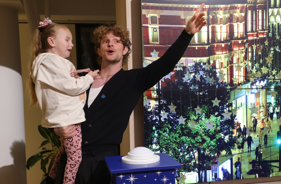 Tom Grennan is focused on scoring the Christmas No1, pictured turning on Christmas lights at London’s Oxford Street with little Emily Mullen