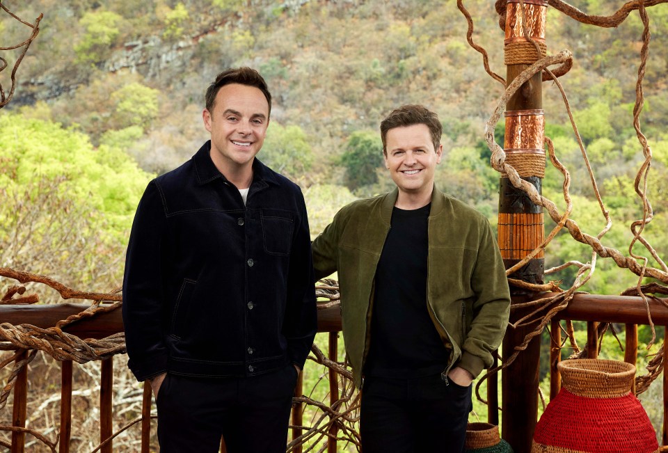 two men are standing next to each other on a balcony and one of them is wearing a green jacket