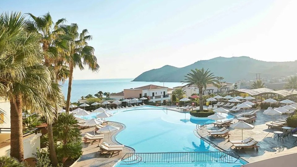 a large swimming pool surrounded by chairs and umbrellas