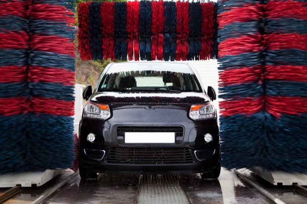 a black car is going through a car wash with red and blue brushes