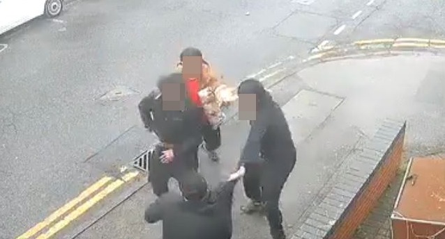 a group of people are standing on the side of a street .