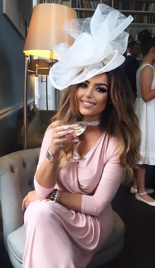 a woman in a pink dress is sitting in a chair holding a glass of wine