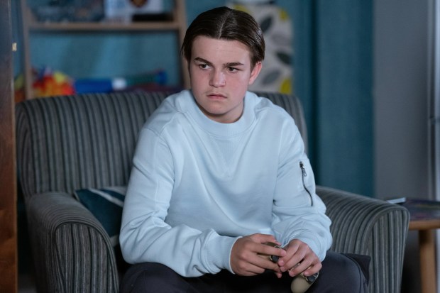 a young man is sitting in a chair with his hands folded