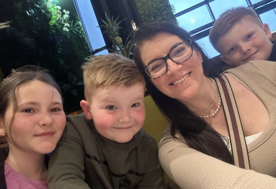 a woman wearing glasses smiles with three children