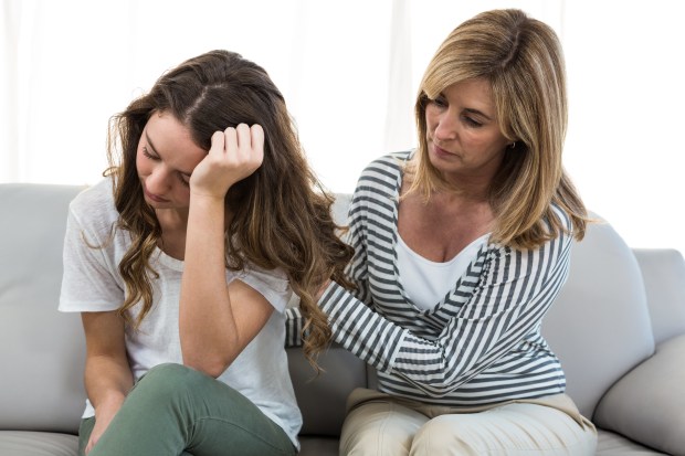 a woman is comforting another woman who is sitting on a couch