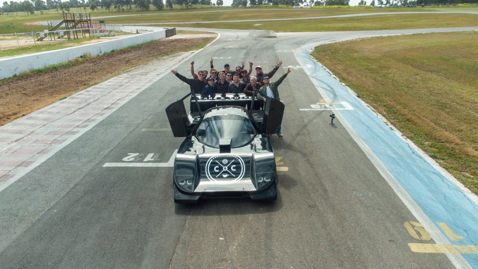 a group of people are posing for a picture in front of a car that says cxc