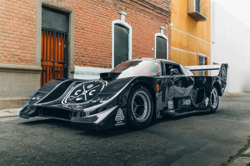 a black race car is parked in front of a brick building