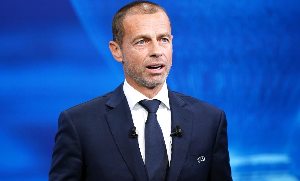 a man in a suit and tie with a uefa logo on his pocket