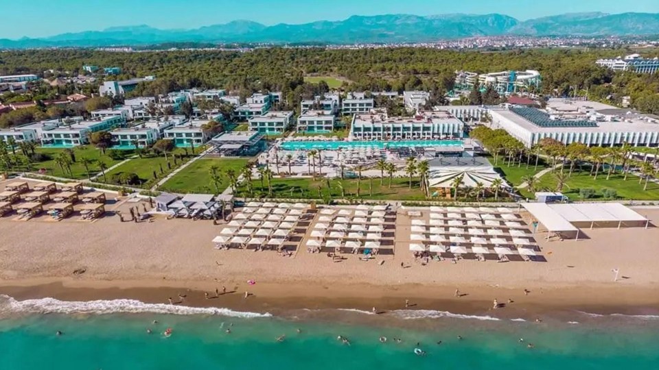 an aerial view of a beach with white umbrellas