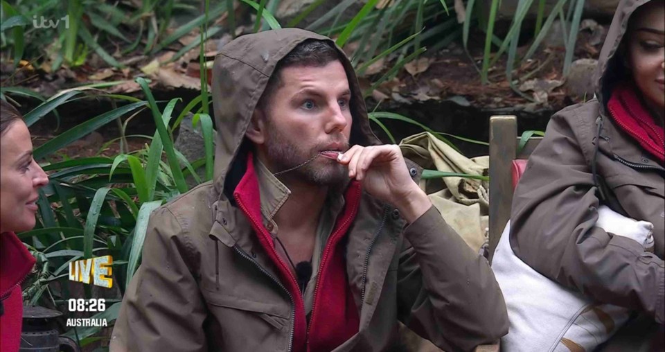 a man in a hooded jacket sits in front of a tv screen that says itv 1