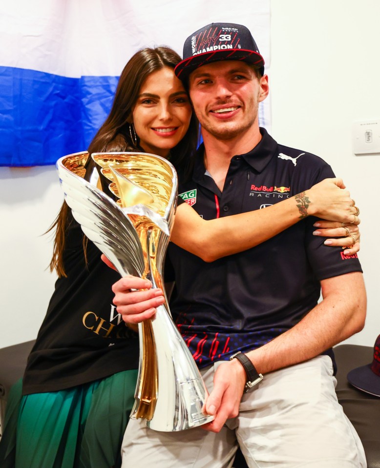 a man in a red bull shirt holds a trophy next to a woman