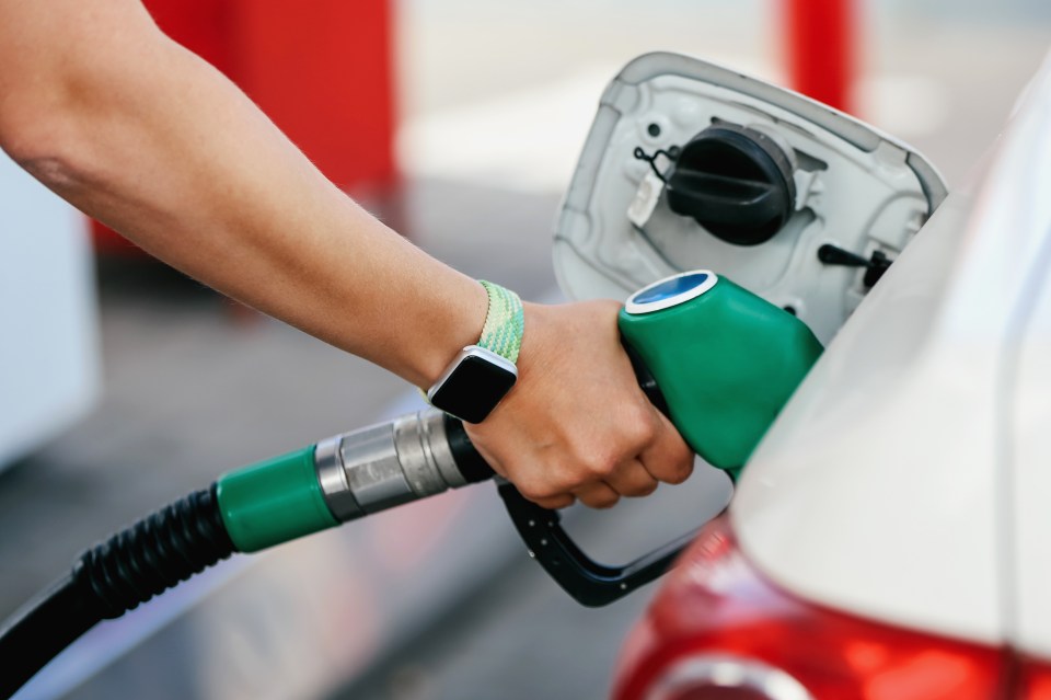 a person wearing an apple watch is pumping gas into a car