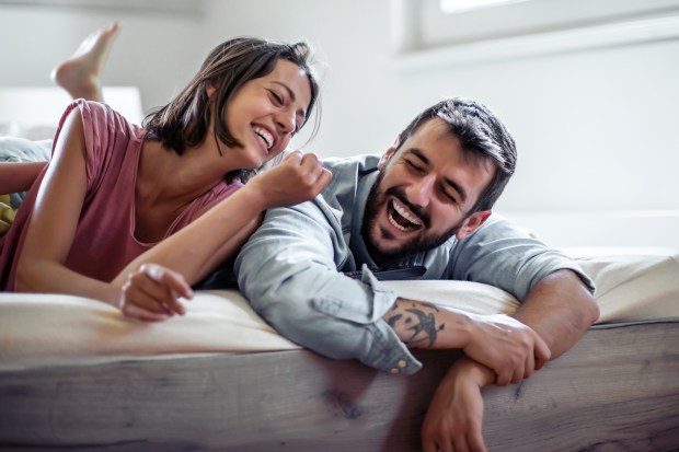 a man with a tattoo on his arm laughs with a woman