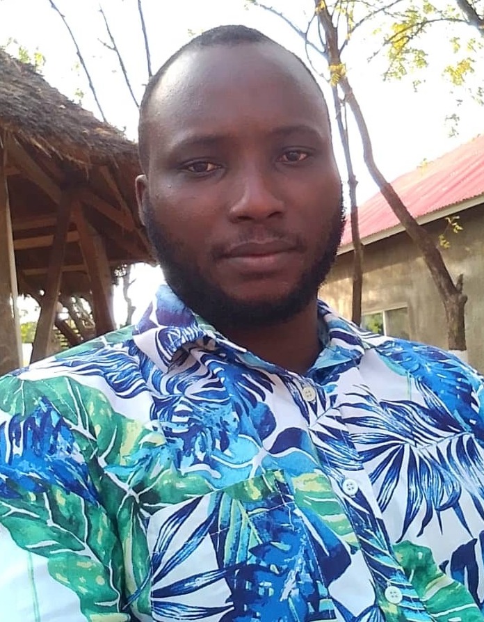 a man wearing a floral shirt stands in front of a tree