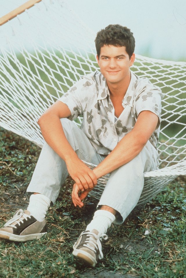 a young man sits in a hammock with his legs crossed