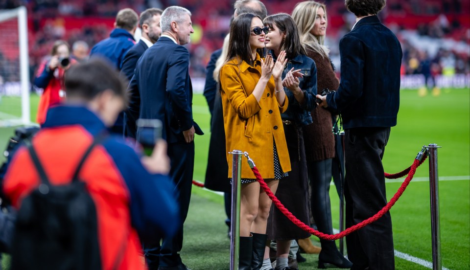 a group of people standing on a soccer field behind a red rope