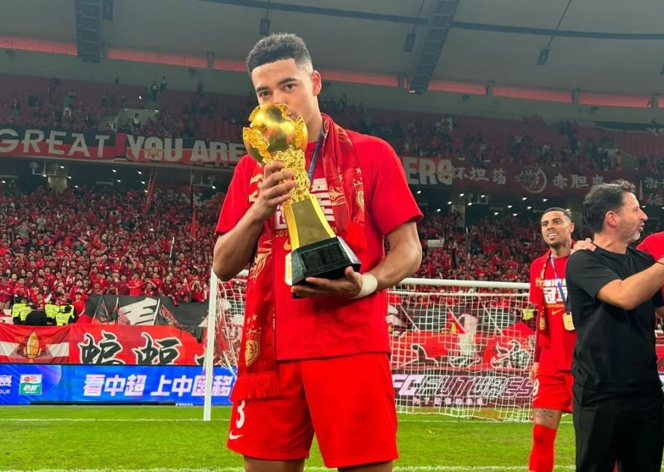 a soccer player holds a trophy in front of a crowd that says great you are