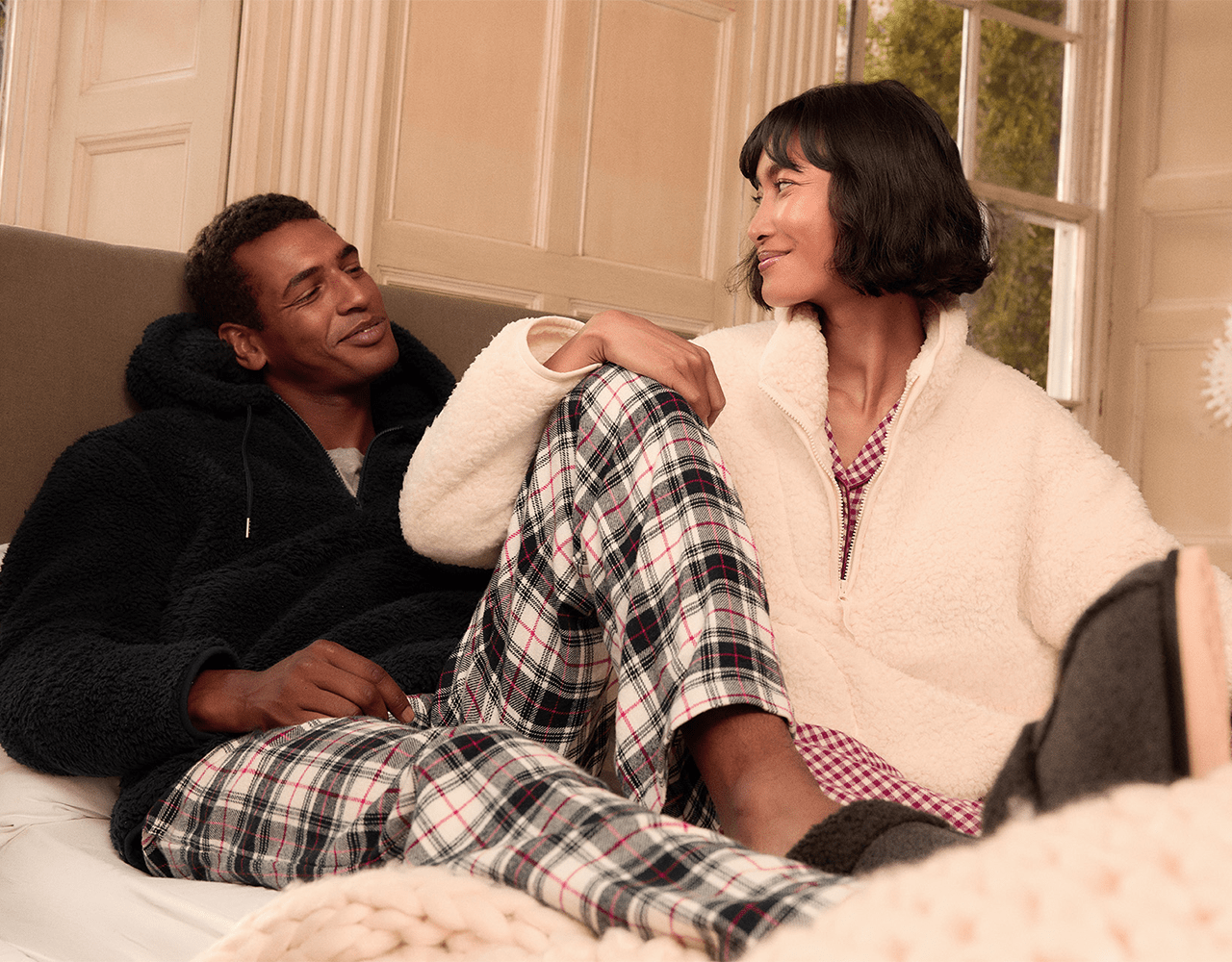 a man and a woman are sitting on a bed looking at each other