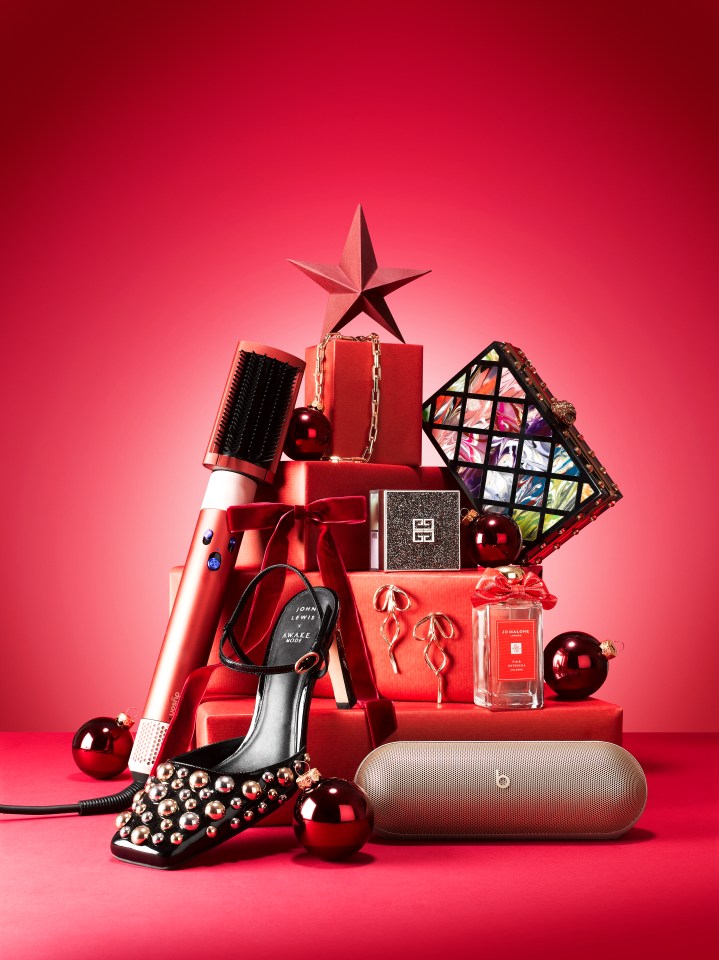 a stack of red gifts including a shoe and a bottle of jo malone perfume