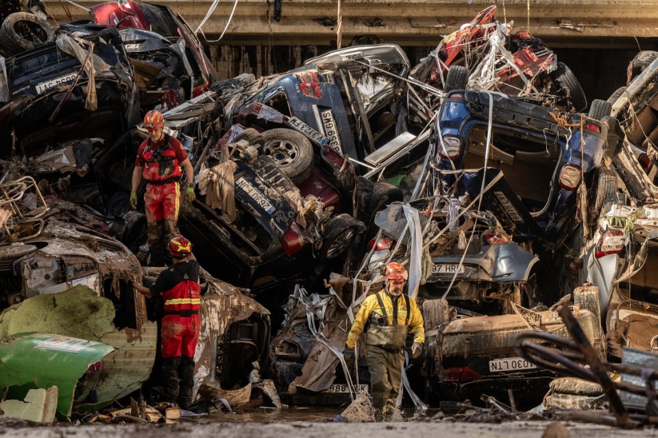 Members of the fire brigade carry out work as cars and debris block a tunnel on the border of Benetusser and Alfafar municipalities