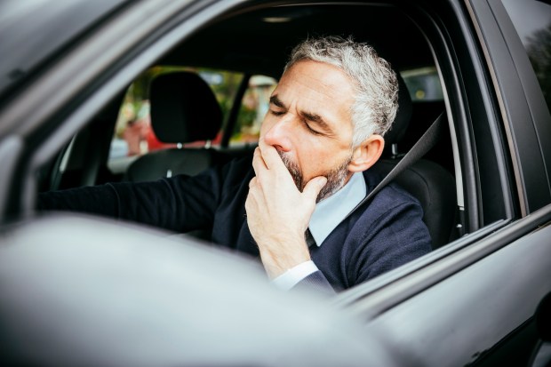 a man is yawning while sitting in a car