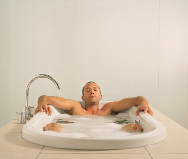 a man is taking a bath with his eyes closed