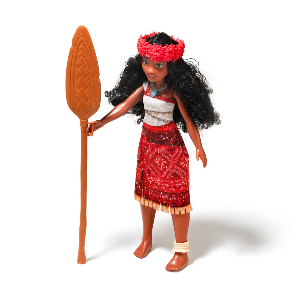 a doll in a red dress is holding a wooden stick