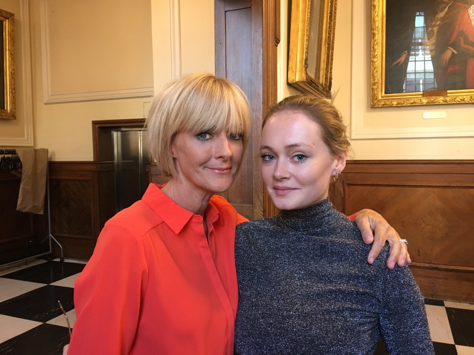 two women posing for a picture in front of a painting