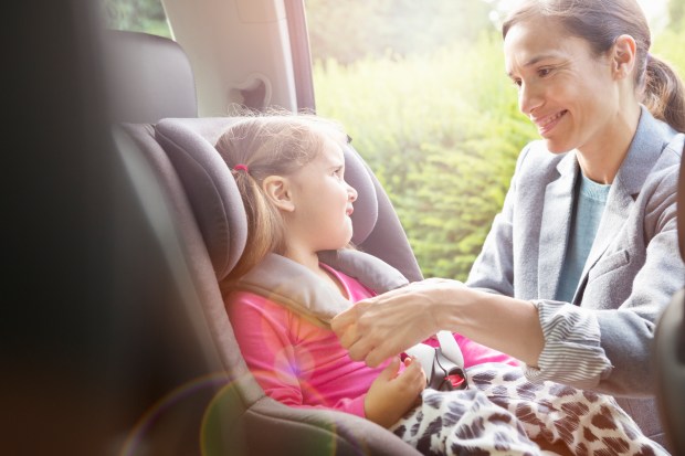 a woman is putting a child in a car seat