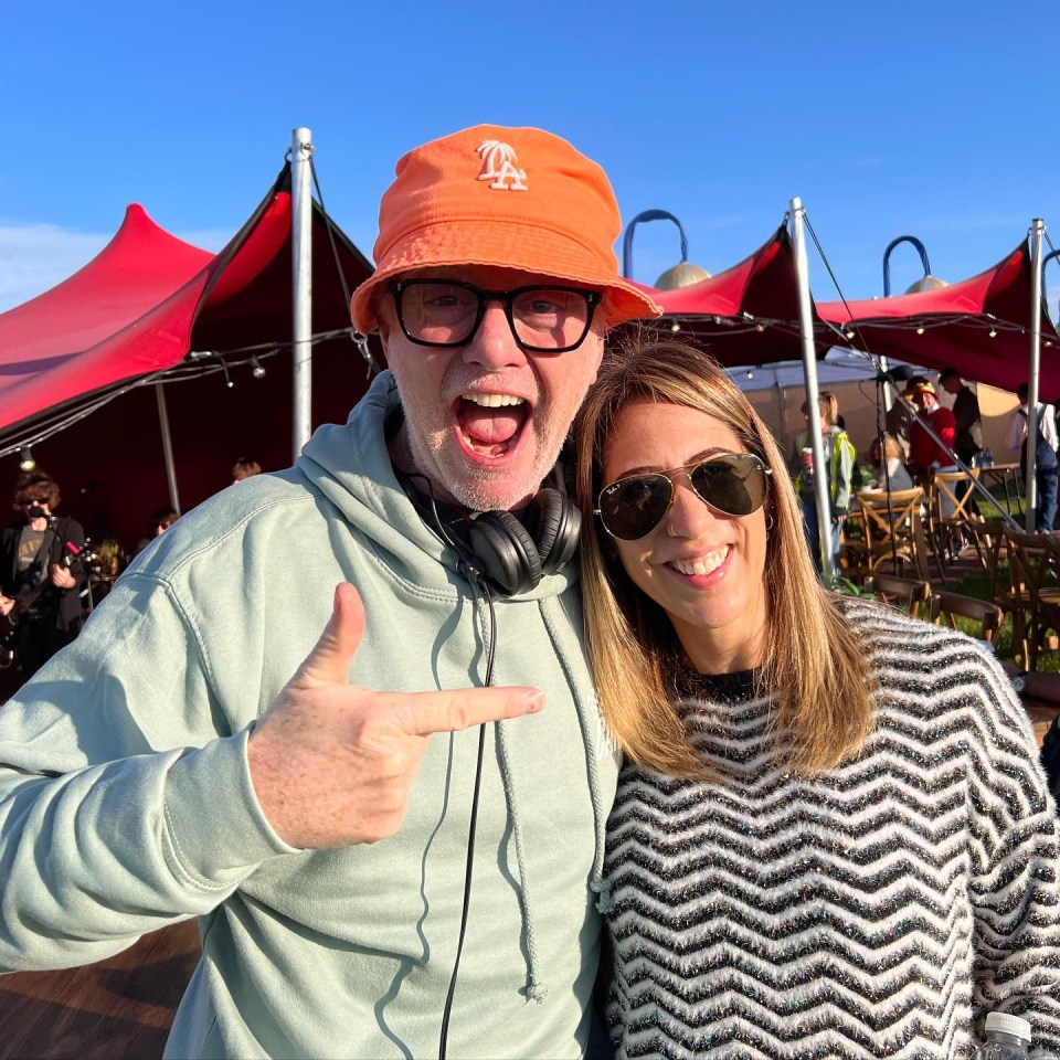 a man wearing an orange la hat stands next to a woman wearing sunglasses