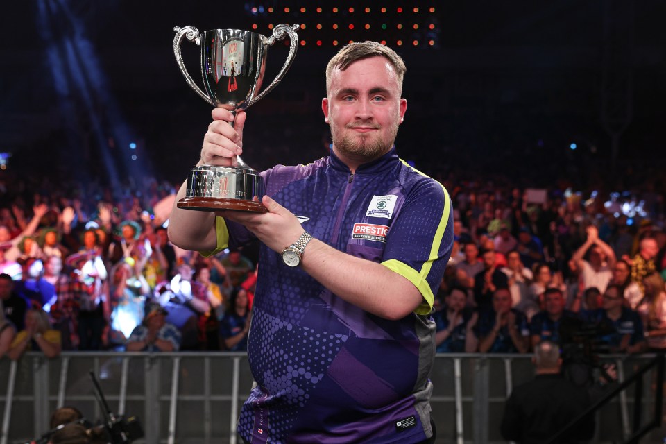 a man holding a trophy with the word prestige on his shirt