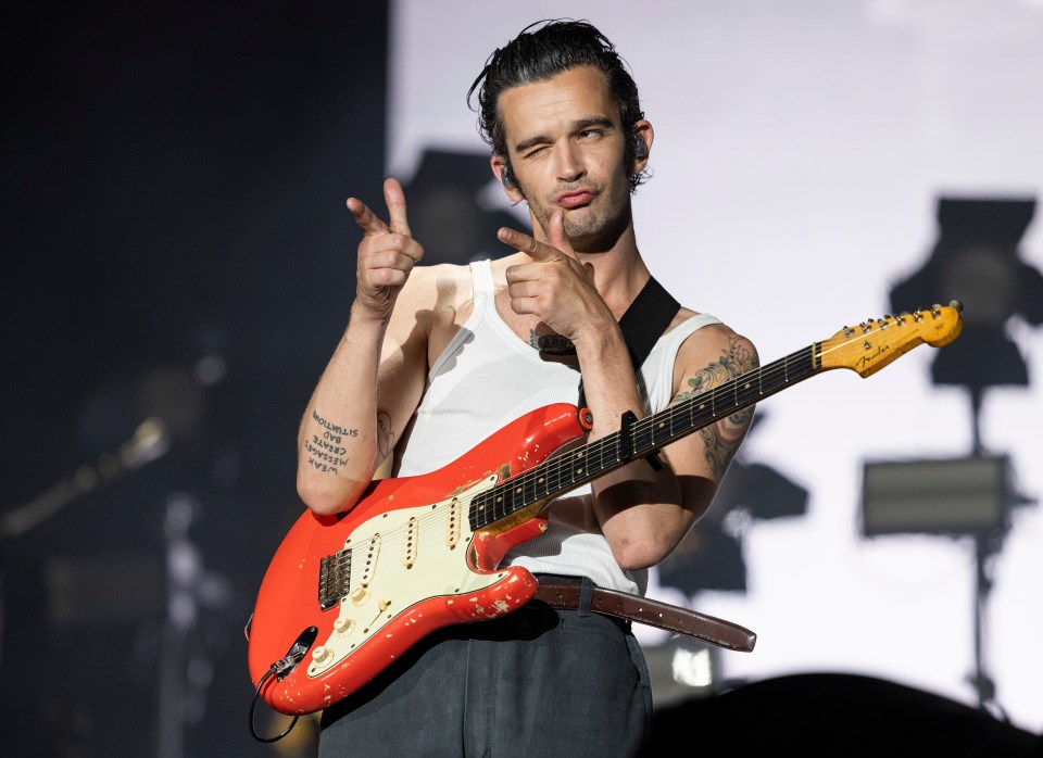 a man with a tattoo on his arm playing a red guitar