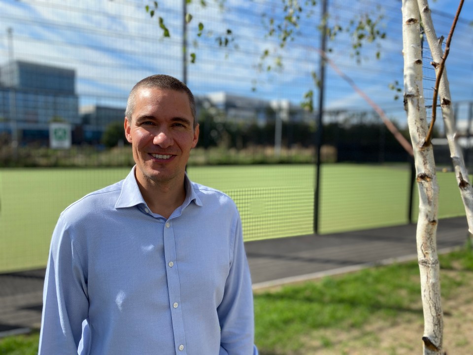 a man in a blue shirt stands in front of a green field