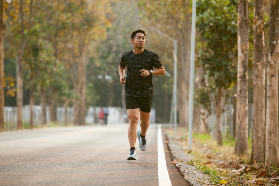 a man in a black shirt is running down a road